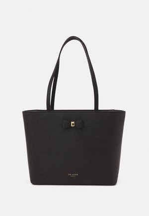 Czarna torba typu tote ze skóry z podwójnymi paskami na ramię, małą ozdobną kokardą ze złotym akcentem oraz logo "Ted Baker London" w kolorze złotym na środku na dole.