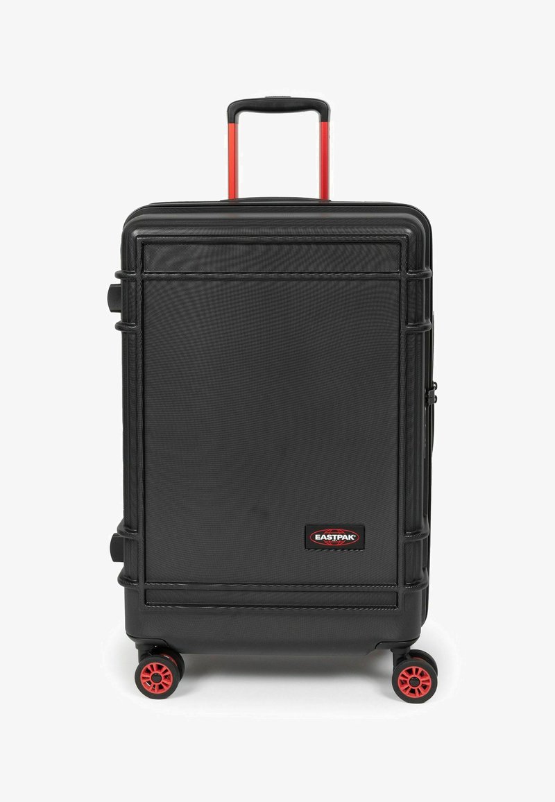 Černý tvrdý kufr s texturovaným povrchem, červenými koly a výsuvnou černou rukojetí. Na přední straně je značka Eastpak.