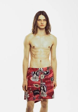 Bañador corto rojo con estampado y diseños gráficos, con acentos de texto, que cuenta con una cintura con cordón y una tela ligera.