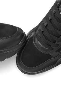 Schwarze Sneaker aus einer Kombination von glattem Leder und Wildleder. Runde Zehenpartie, strukturierte Zunge und schwarze Schnürsenkel.