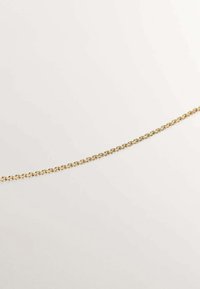 Collar de cadena de oro que presenta eslabones ovalados interconectados con un acabado pulido, descansando sobre un fondo neutro claro.