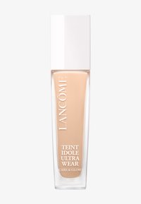 Lancôme Teint Idole Ultra Wear Care & Glow flytende foundation i beige nyanse med hvit rektangulær hette på hvit bakgrunn.