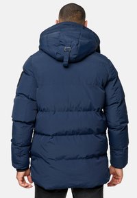 Marineblå dunjakke med hætte, med et quiltet design og sidelommer. Lavet af glat, holdbart materiale. Ingen synlige metaldele.