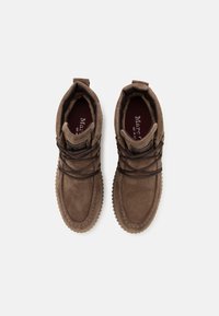 Ruske mokasinke iz zamšene kože s debelimi gumijastimi podplati in temnimi vezalkami, gledano s ptičje perspektive na beli podlagi.