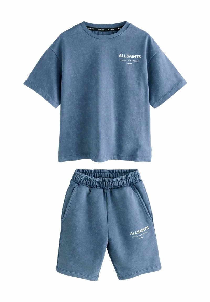 Lyseblå bomulds loungewear sæt, der inkluderer en løs t-shirt med rund hals og broderet logo, samt matchende shorts med elastisk talje.