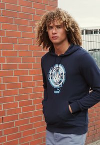 Felpa navy in misto cotone, con una grande grafica azzurro chiaro del Manchester City e tasca a marsupio frontale.