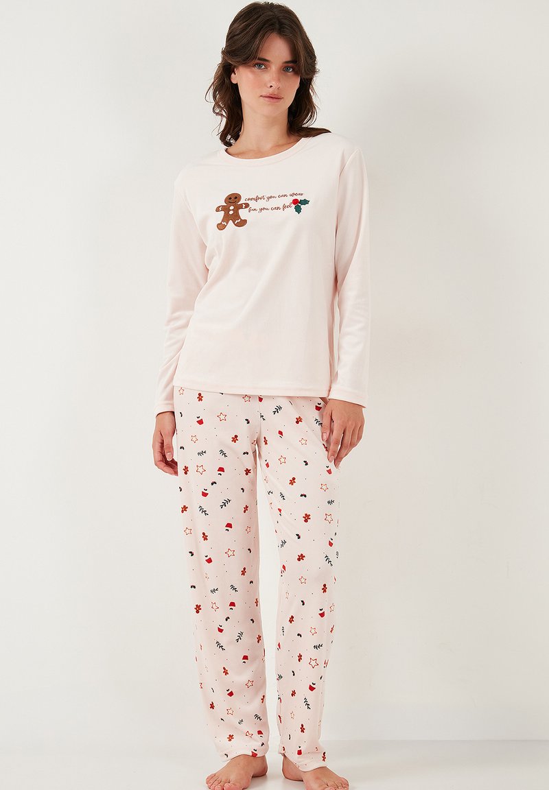 Pitkähihaiset vaaleanpunaiset pyjaman paita, jossa on piparkakkumiehen grafiikka ja teksti, yhdistettynä vaaleanpunaisiin housuihin, joissa on värikkäitä kukka- ja tähtikuvioita.