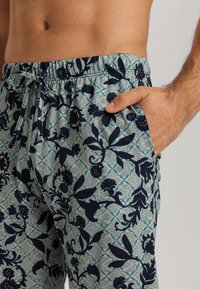 Mönstrade badbyxor för herrar i ljus teal med mörk marinblå blomsterdesign, elastisk midja, dragsko och sidofickor.