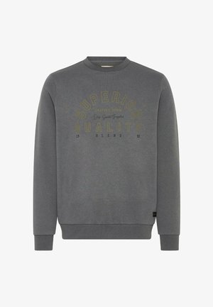 Sudadera gris de cuello redondo con puños y dobladillo acanalados, que presenta el texto "CALIDAD SUPERIOR" en impresión amarilla y negra en la parte frontal.