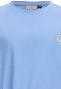Jasnoniebieska koszulka z krótkim rękawem, wykonana z miękkiej bawełny. Posiada okrągły dekolt oraz nadrukowane logo w jasnopomarańczowym kolorze z przodu.