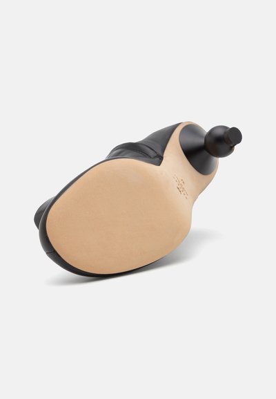 Talpa de pantof din piele neagră, cu o textură netedă, formă rotundă și o ușoară curbură. Talpa de culoare deschisă, cu marcaje minime.
