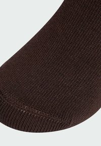 Brązowa skarpetka z teksturowanym wzorem dzianiny, z gładkim szwem palców i lekko ściągniętym mankietem, podkreślająca swoją miękką strukturę materiału.