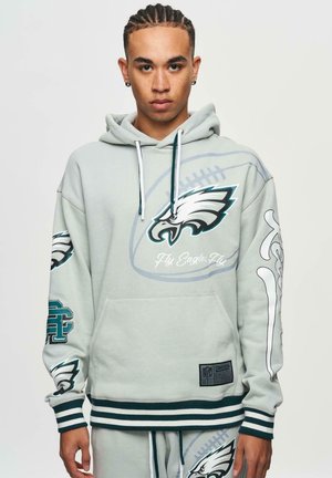 Sweatshirt gris clair avec logo des Eagles, poche avant, poignets et ourlet côtelés, et détails graphiques sur les manches. Fabriqué à partir d'un tissu doux et texturé.