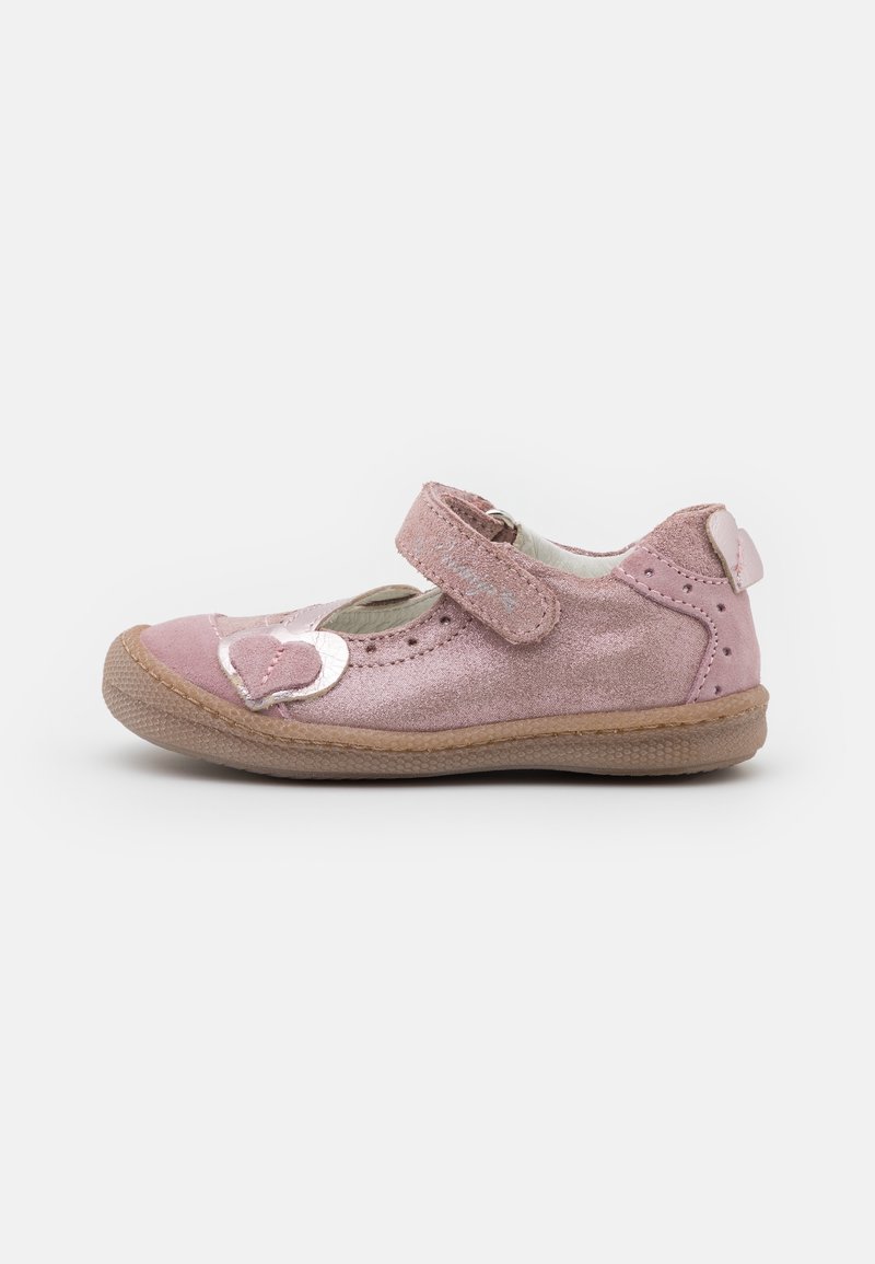 Zapato de charol rosa para niña pequeña, con correa de velcro ajustable y decoraciones en forma de corazón en la punta y en la parte trasera, suela de goma, vista lateral sobre fondo blanco.