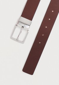 Καφέ δερμάτινη ζώνη με ασημένια ορθογώνια αγκράφα, διαθέτει πέντε ρυθμιζόμενες τρύπες και λεία υφή. Περιλαμβάνει χαραγμένο το λογότυπο της μάρκας στην αγκράφα.