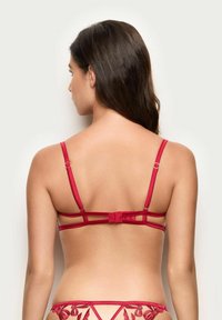 Rød BH med justerbare stropper, der har et design med flere stropper bagpå. Glat tekstur, enkel form, minimal hardware-detaljer og ingen mønstre.