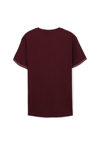T-shirt corto a maniche corte di un marrone scuro uniforme visto da dietro, con cuciture bianche a zigzag lungo gli orli delle maniche.