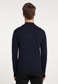 Navy blue knitted sweater with long sleeves and a round neckline. Features a ribbed hem and cuffs, smooth texture, and minimal design.