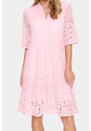 Hellrosa Spitzenkleid mit Ellbogen-langen Ärmeln, V-Ausschnitt und ausgestelltem Saum, getragen von einer Person vor einem schlichten Hintergrund.