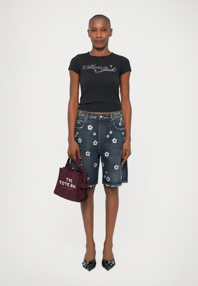 T-shirt noir ajusté avec logo, short en denim avec broderie florale, sac fourre-tout bordeaux et chaussures noires à bout pointu. Tissu lisse et forme structurée.