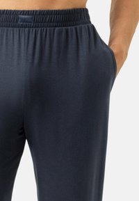 Marineblauwe joggingbroek met elastische taille en zijzakken, gemaakt van zacht, glad stof. Voorzien van een minimalistisch merkembleem op de tailleband.