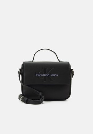 Zwarte crossbodytas van Calvin Klein Jeans met bovenhandvat, verstelbare schouderriem en gegraveerd CK-logo op de voorflap.