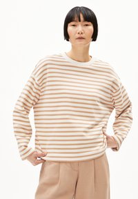Leichtes, langärmeliges gestreiftes Oberteil in Beige und Weiß, mit Rundhalsausschnitt und lockerer Passform, kombiniert mit beigen Hosen.