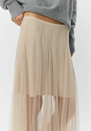 Beige tule rok met een gelaagd ontwerp, doorschijnende textuur en een aangesloten tailleband, gecombineerd met een grijze gebreide trui.