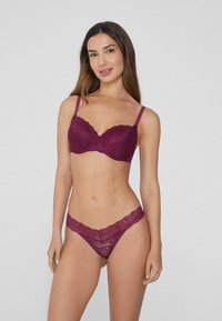 Mauve krajková podprsenka a odpovídající tanga mají vlnité okraje a jemné květinové vzory, jsou navrženy s tenkými ramínky pro bezproblémový vzhled.