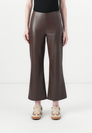 Brune faux skinnbukser med vid benvidde og en glatt tekstur, med høy midje. Kombinert med mønstrede sneakers.
