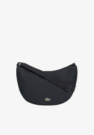 Sac d'épaule noir en forme de croissant avec une bandoulière réglable et un petit logo crocodile vert au centre devant.