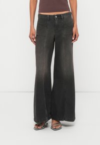 Παντελόνια τζιν με φαρδιά μπατζάκια σε μαύρο χρώμα με ξεθωριασμένο φινίρισμα, με εμπρόσθιες τσέπες και κλείσιμο με κουμπιά. Το ύφασμα έχει λεία υφή.