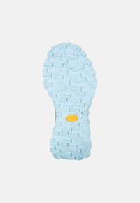 Světle modrá gumová podrážka s výraznými vzory záběru, na které je žluté logo Vibram, navržena pro přilnavost a stabilitu.