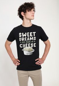Černé bavlněné tričko s grafickým designem, na kterém je text "SWEET DREAMS ARE MADE OF CHEESE" a obrázek šálku sýra.