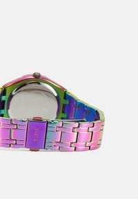 Orologio metallico con bracciale a catena multicolore, dotato di cassa rotonda e retro riflettente. Inciso "GUESS" sulla chiusura.