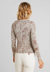 Langärmliges Oberteil mit einem braun-beigen Schlangenprint, schlanker Schnitt und weichem Material, gestaltet mit einem Rundhalsausschnitt und nahtloser Verarbeitung.