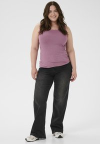 Top violet cu nervuri și blugi negri evazați, asortați cu adidași albi. Textură netedă cu siluetă ajustată și potrivire lejeră în pantaloni.