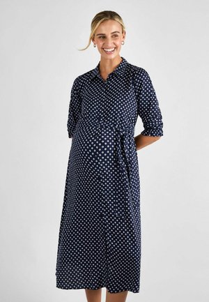 Abito premaman blu navy con colletto, maniche a tre quarti e vita con doppio nodo, caratterizzato da un motivo floreale bianco.