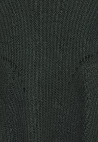 Dunkelgrüner Strickpullover aus weichem Garn. Er hat eine gerippte Textur, einen runden Ausschnitt und einen lockeren Schnitt mit kunstvollen Nähten.