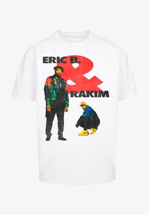 White cotton t-shirt featuring a graphic print of two figures. One stands with a multicolored jacket, the other crouches in a blue outfit with yellow shoes.