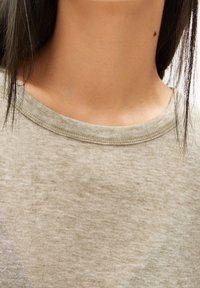 Světlobéžové bavlněné tričko s žebrovaným kulatým výstřihem. Tkanina má jemný,Texturovaný vzhled.