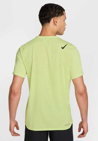 T-shirt de sport Nike vert lime à manches courtes, avec un design texturé et perforé et un logo noir au dos.