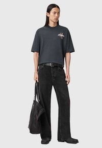 Σκούρο γκρι υπερμεγέθη μπλουζάκι με γραφικό σχέδιο, συνδυασμένο με μαύρο τζιν παντελόνι φαρδιάς γραμμής. Τα αξεσουάρ περιλαμβάνουν μαύρη ζώνη και τσάντα.