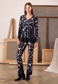 Navy and cream patterned long-sleeve top with V-neck, paired with matching pants. Both have a soft texture and contrasting black trim.