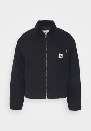 Jaqueta de ganga preta com colarinho de veludo, fecho dianteiro de zipper e um bolso no peito com um zipper dourado e um emblema no lado esquerdo.
