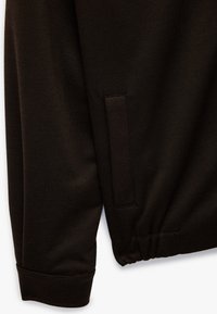 Sort jakke stof med en tekstureret overflade, der har en synlig lomme og et manchetærme design. Materialet ser holdbart og robust ud.