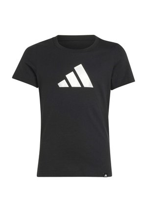 Joven mujer con cabello oscuro recogido en una coleta, que lleva una camiseta negra de Adidas y pantalones deportivos gris claro con logos de Adidas.