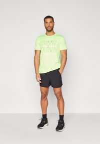 Camiseta deportiva de un brillante color verde neón con el texto "NUNCA DEJES DE COMPETIR", combinada con shorts negros y zapatillas deportivas negras. Diseño simple.