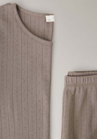 Haut sans manches en maille beige et pantalon assorti à taille élastique avec petits motifs floraux verticaux sur fond clair.
