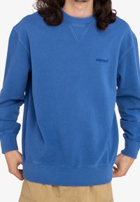 Sweat-shirt bleu en tissu mélange de coton, avec un col rond, des poignets et un ourlet côtelés, arborant un petit logo embossé sur la poitrine.